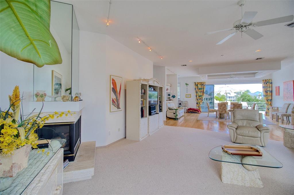A spacious living room features a fireplace, carpeted flooring, and a view of the patio — 131 SANDS POINT DRIVE, TIERRA VERDE, FL