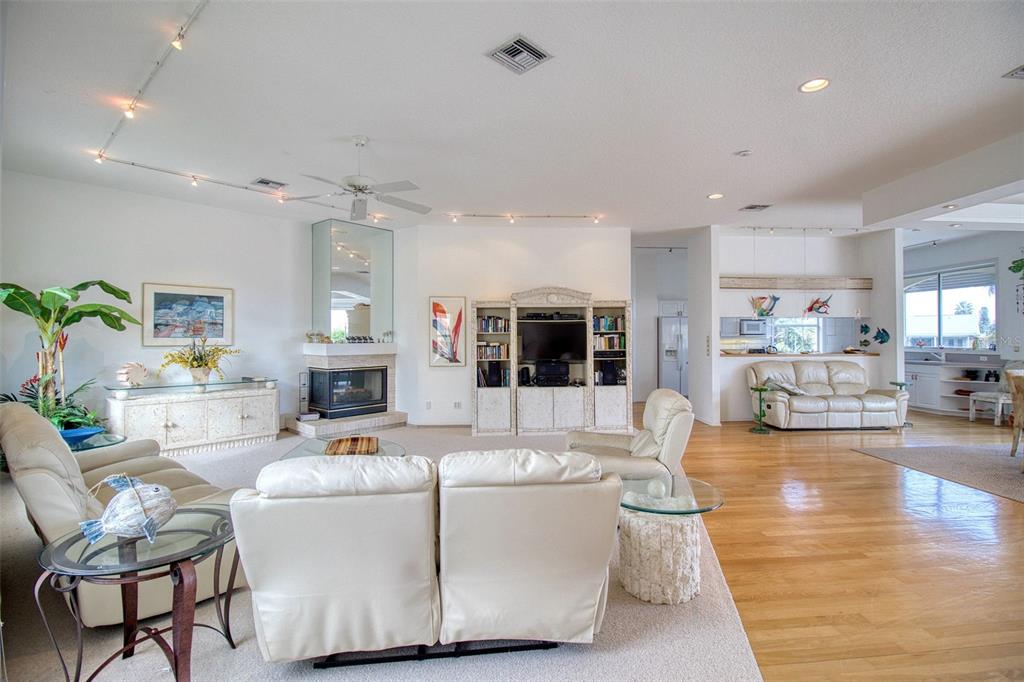 A spacious living room features white leather furniture, a fireplace, and hardwood and carpeted floors — 131 SANDS POINT DRIVE, TIERRA VERDE, FL