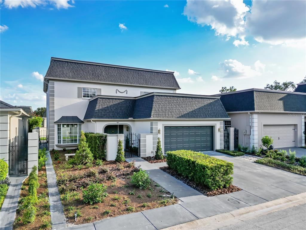 A two-story house with a dark mansard roof, white stucco walls, and a two-car garage — 2186 COUNTRYSIDE CIRCLE N, ORLANDO, FL