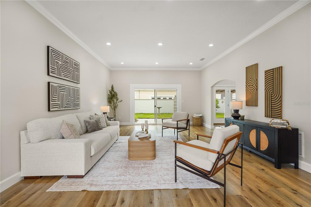 A bright room with white walls, crown molding, and wood-look flooring leads to an arched doorway — 2186 COUNTRYSIDE CIRCLE N, ORLANDO, FL