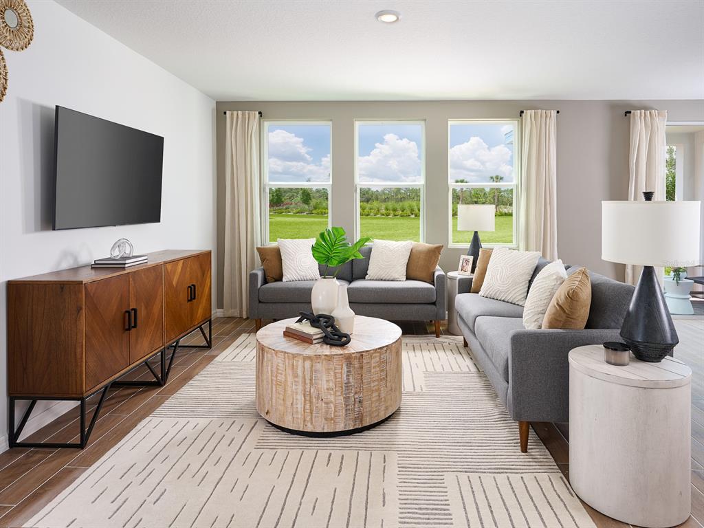 A living room features two gray sofas, a round wooden coffee table, and a media console — 638 PENNYWORT STREET, LAKE ALFRED, FL