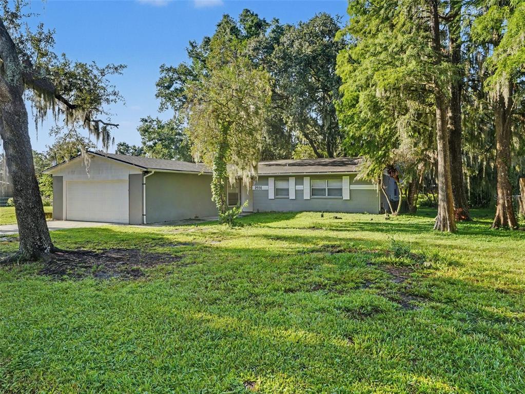 A single-story house with a white garage and gray siding sits on a grassy lot — 2938 NORTHBROOK LANE, LAKELAND, FL