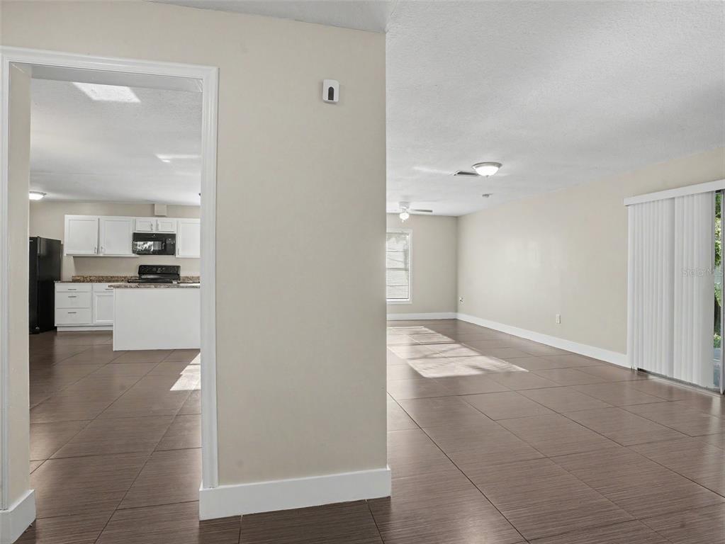 A view from a tiled room looking into an open kitchen with white cabinets — 2938 NORTHBROOK LANE, LAKELAND, FL