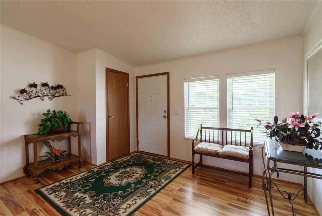 An entryway with wood flooring, a green area rug, a wooden bench, and two tables — 13259 SE 49TH COURT, BELLEVIEW, FL