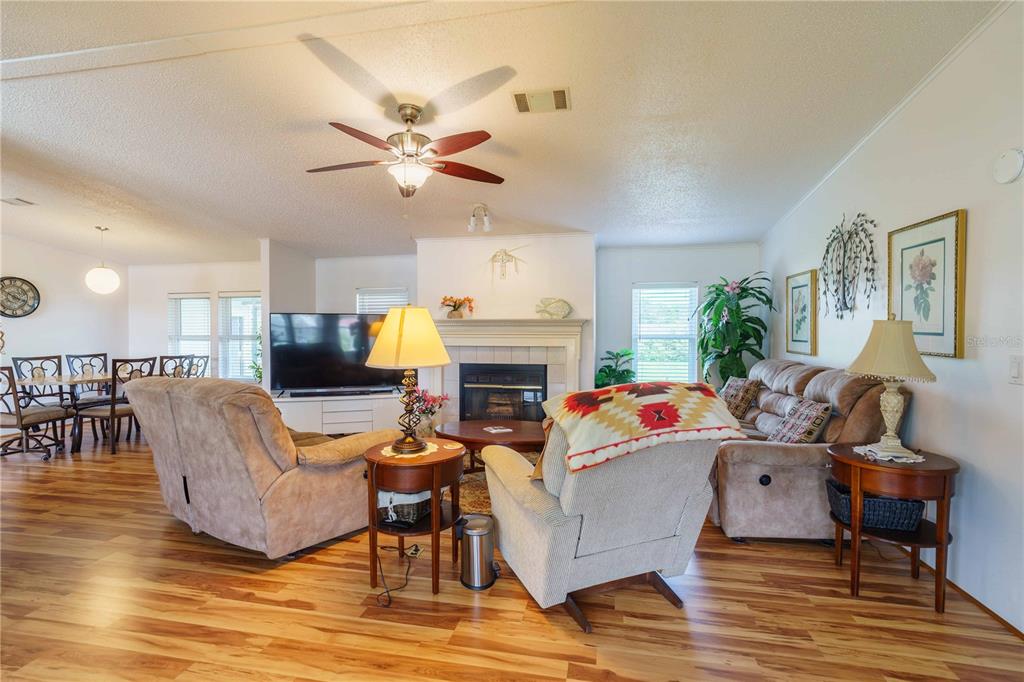A living room features wood flooring, a fireplace, a ceiling fan, and comfortable seating furniture — 13259 SE 49TH COURT, BELLEVIEW, FL