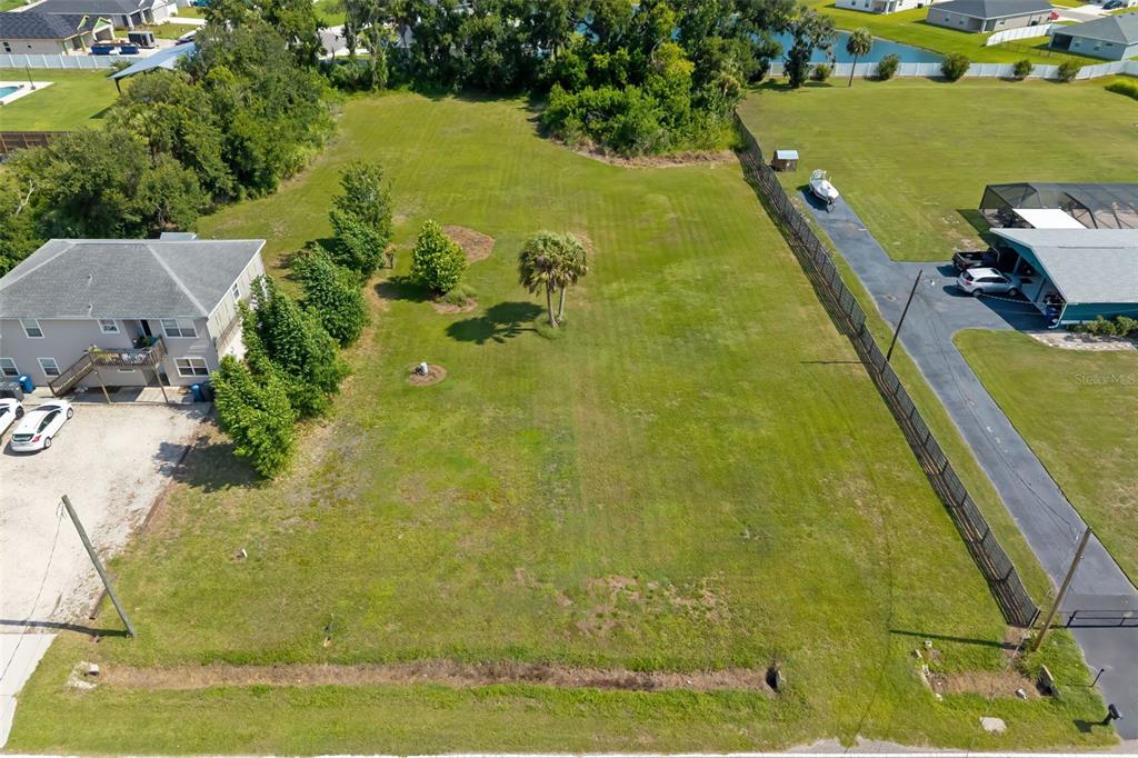 An aerial view shows a vacant, grassy rectangular lot situated between two residential properties — 2612 61ST STREET E, PALMETTO, FL
