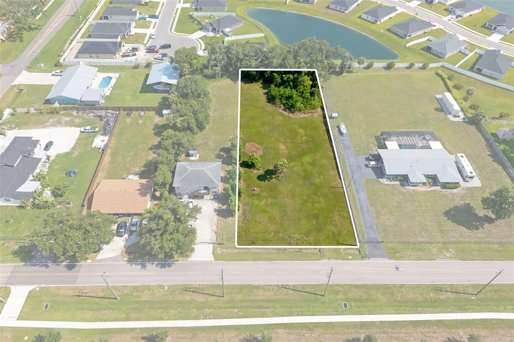 An aerial view shows a rectangular vacant lot outlined in white between two residential properties — 2612 61ST STREET E, PALMETTO, FL