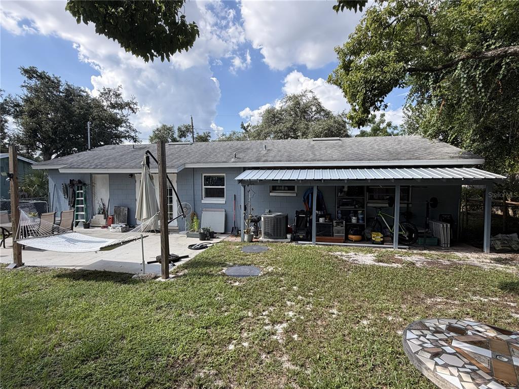 The backyard of a single-story house features a concrete patio, a hammock, and a covered carport — 4180 POINSETTIA AVENUE, MOUNT DORA, FL