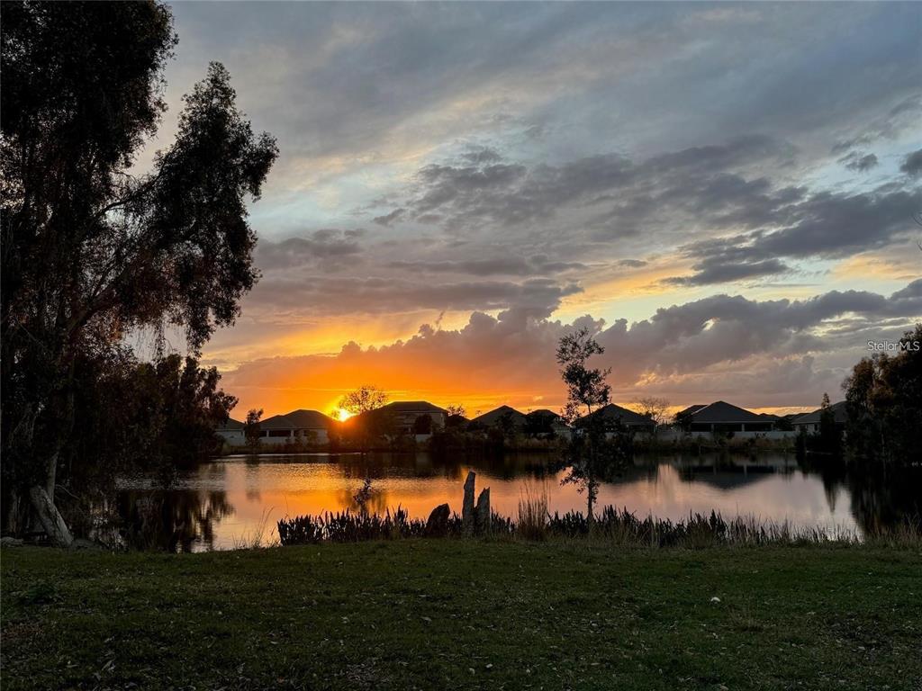 A sunset view over a lake with houses in the background and trees in the foreground — 1888 DRULINER ROAD, ST CLOUD, FL