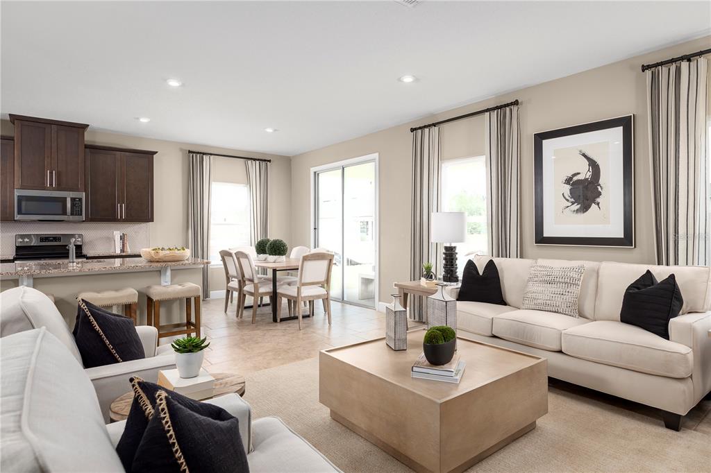 An open-concept living and dining area features a kitchen with dark wood cabinets and tile flooring — 291 PRICKLY PEAR COURT, LADY LAKE, FL