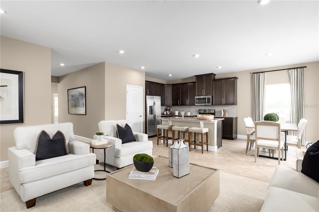 An open-concept kitchen with dark cabinets and an island overlooks a living and dining area — 291 PRICKLY PEAR COURT, LADY LAKE, FL