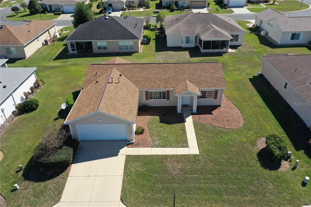 A single-story, tan-sided house with a two-car garage and a brown shingled roof — 13828 SE 85TH CIRCLE, SUMMERFIELD, FL