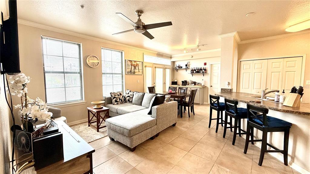 An open-concept living and dining area features a sectional sofa, kitchen island, and tile flooring — 911 N ORANGE AVENUE UNIT 243, ORLANDO, FL