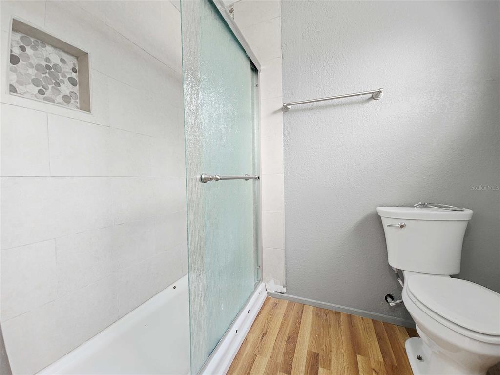 A bathroom features a shower with a glass door, a toilet, and wood-look flooring — 416 BAL HARBOR BOULEVARD, PUNTA GORDA, FL