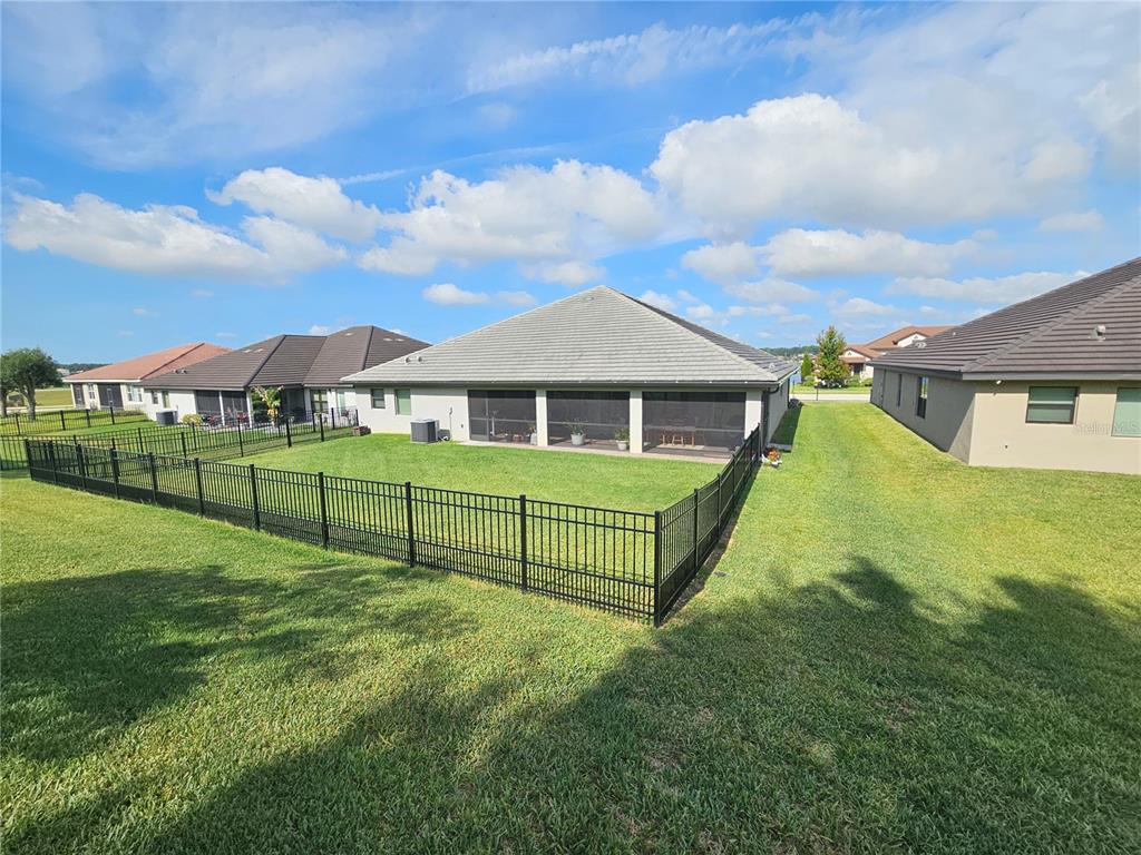 A covered patio features a dining table, hanging chairs, potted plants, and brick flooring — 4222 JULIANA LAKE DRIVE, AUBURNDALE, FL