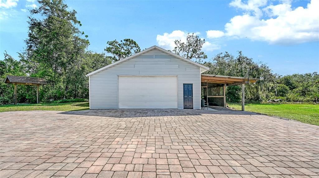 A two-story house with light blue siding, a metal roof, and stone-accented porch columns — 28401 104TH DR E, MYAKKA CITY, FL