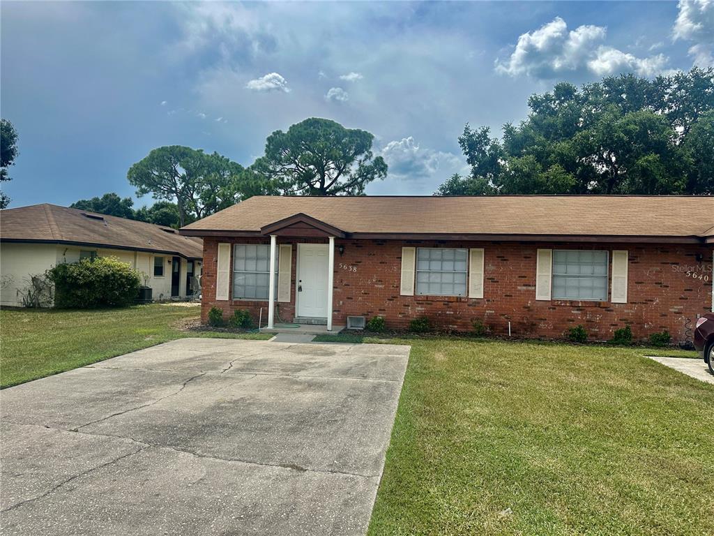A single-story brick duplex with a concrete driveway and a brown shingled roof — 5638 STRUTHERS COURT, WINTER HAVEN, FL