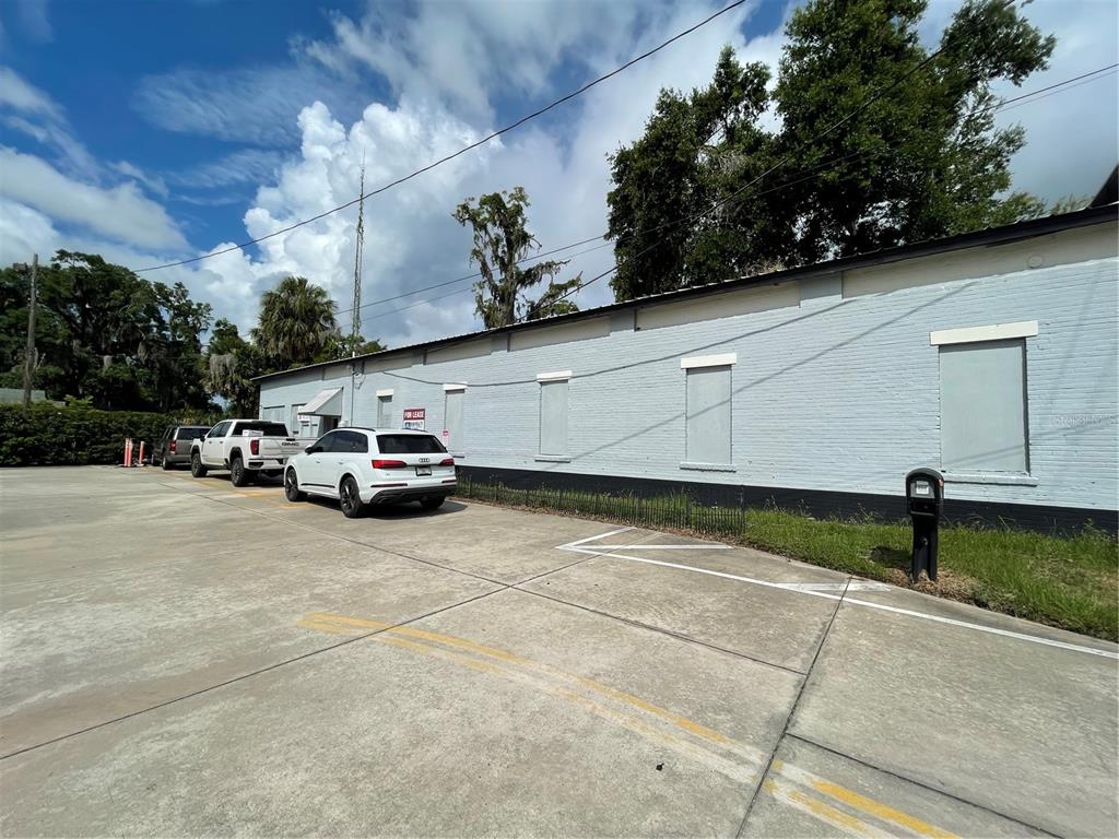 A light blue brick building with boarded-up windows sits beside a concrete parking lot — 55 GUERRANT STREET, UMATILLA, FL