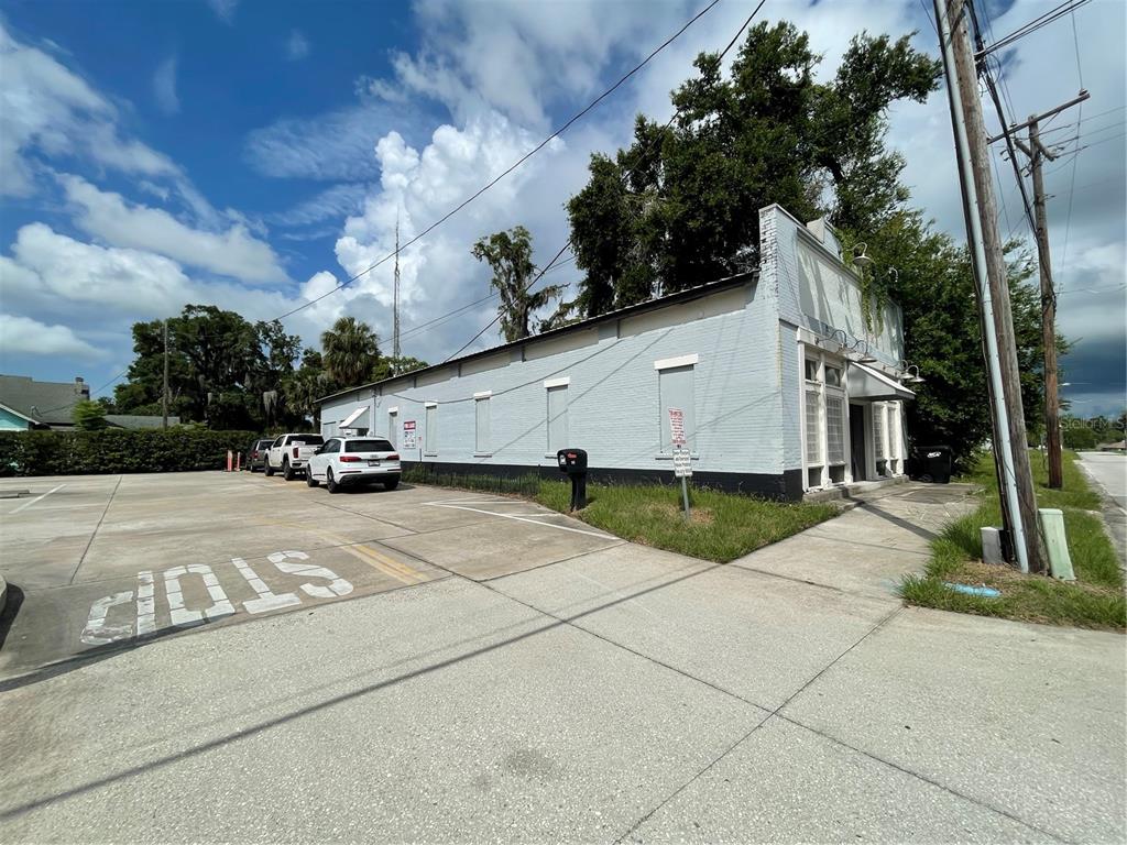 A light-colored, single-story brick commercial building sits next to a paved parking lot — 55 GUERRANT STREET, UMATILLA, FL