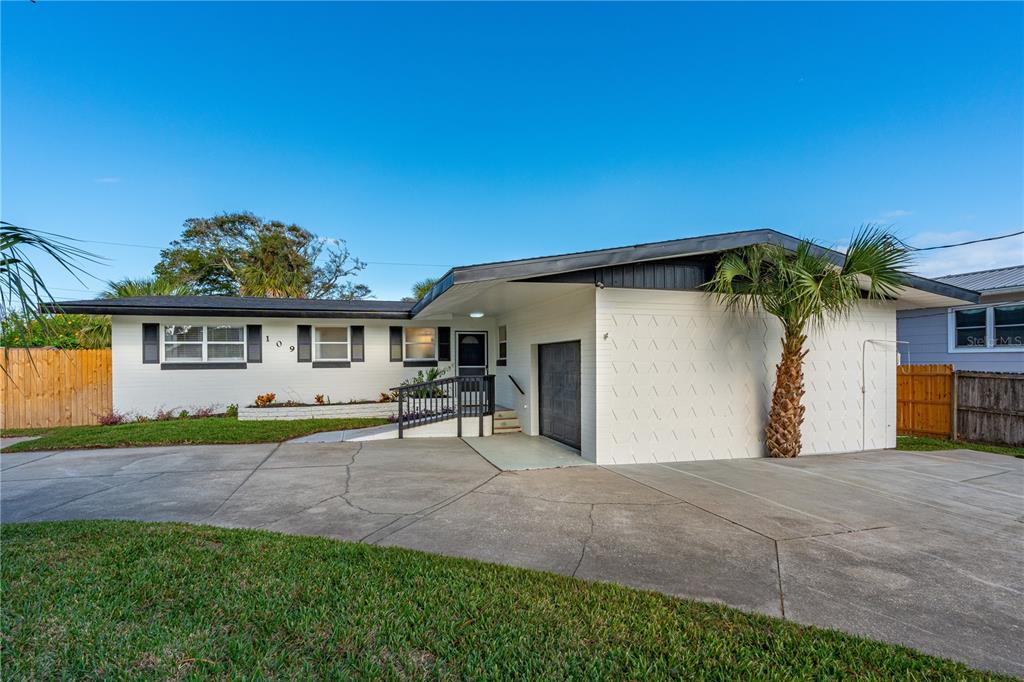 A single-story white house with a black roof, a garage, and a concrete driveway — 109 STANDISH DRIVE, ORMOND BEACH, FL