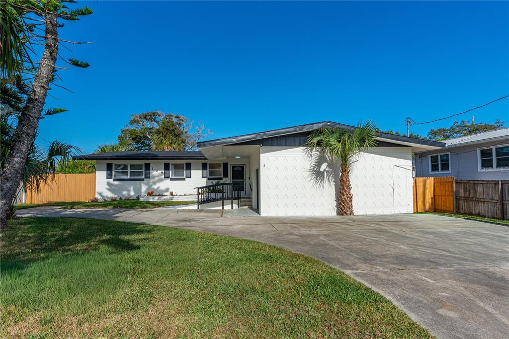 A single-story white house with a concrete driveway and a palm tree in the front — 109 STANDISH DRIVE, ORMOND BEACH, FL