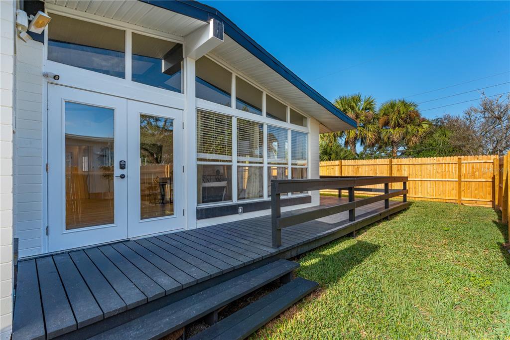 A dark wooden deck with stairs leads to white French doors on a house exterior — 109 STANDISH DRIVE, ORMOND BEACH, FL