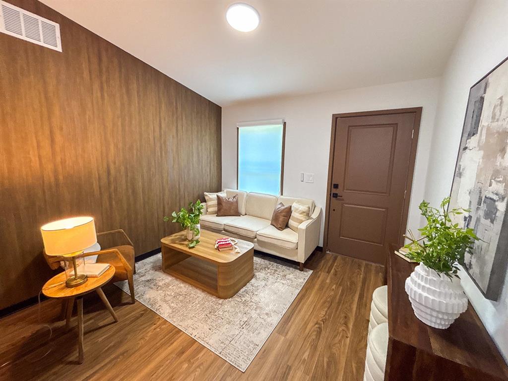 A living room features wood-look flooring, a wood-paneled accent wall, a sofa, and a coffee table — 5620 VIRTUDES STREET, SEBRING, FL