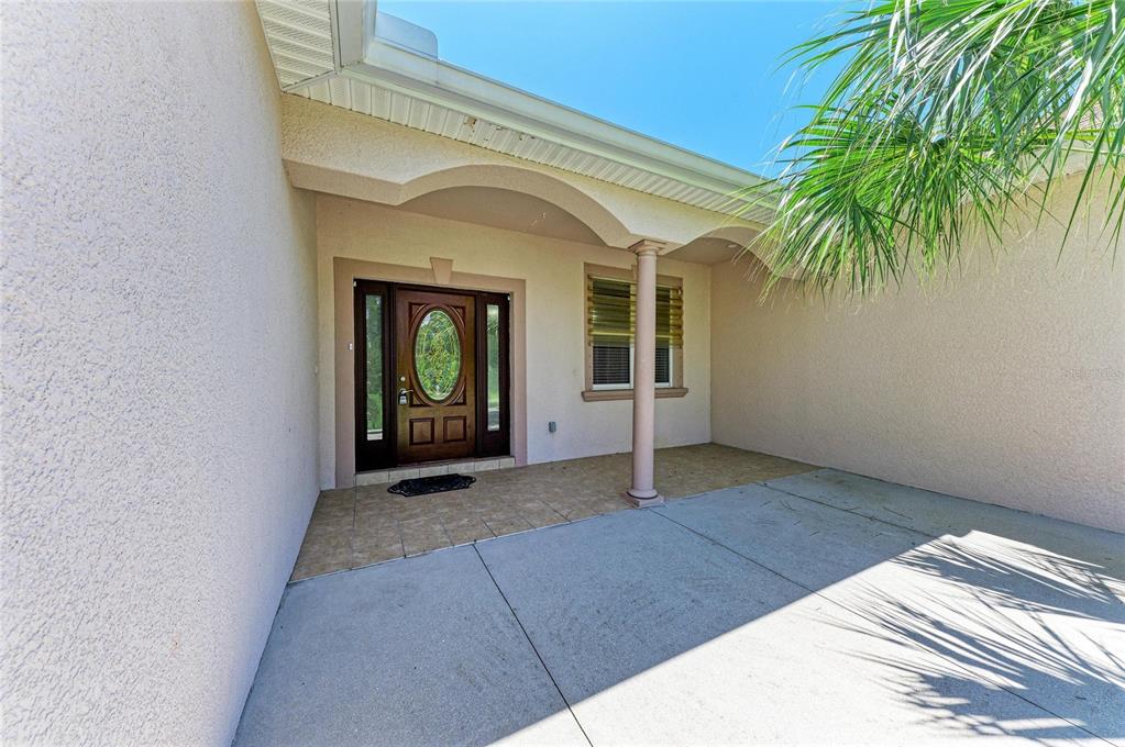 A covered entryway features a brown front door, a single column, and tiled flooring — 3190 BAY CITY TERRACE, NORTH PORT, FL