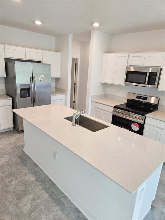 A kitchen island with a sink overlooks an open living area with tile flooring — 757 REGGIE ROAD, WINTER HAVEN, FL