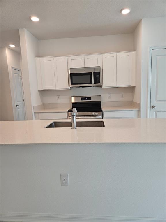 A kitchen island with a stainless steel dishwasher and sink faces an open living area — 757 REGGIE ROAD, WINTER HAVEN, FL