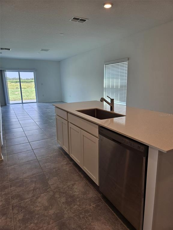A kitchen features white cabinets, stainless steel appliances, and a quartz-topped island with a sink — 757 REGGIE ROAD, WINTER HAVEN, FL