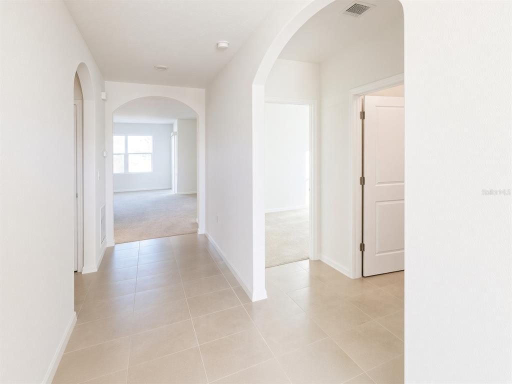 A tiled hallway leads to an arched entryway opening into a carpeted living area — 3499 N VONNEGUT PT, BEVERLY HILLS, FL