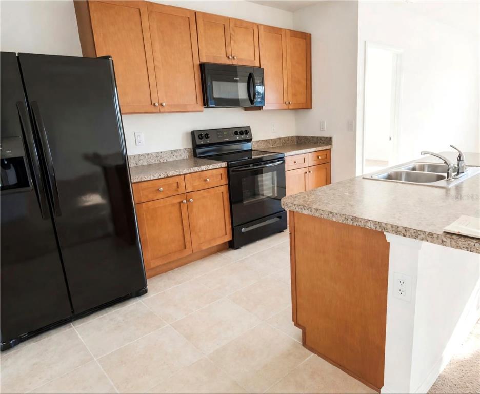 A kitchen features wood cabinets, black appliances, granite countertops, and a central island — 3499 N VONNEGUT PT, BEVERLY HILLS, FL