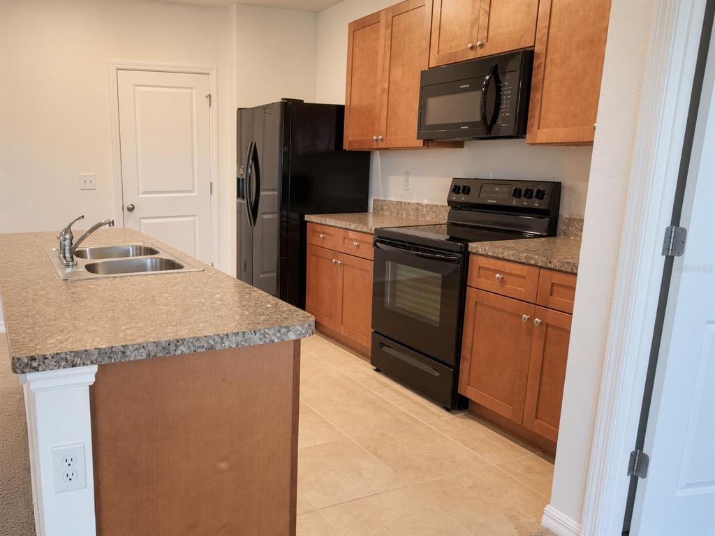 A kitchen features wood cabinets, black appliances, and a granite-topped island with a sink — 3499 N VONNEGUT PT, BEVERLY HILLS, FL