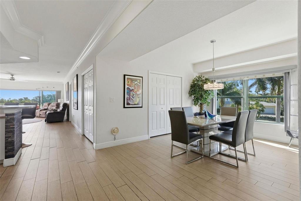 A dining area with a glass table and chairs sits adjacent to a living room — 1695 PINELLAS BAYWAY S UNIT E4, TIERRA VERDE, FL