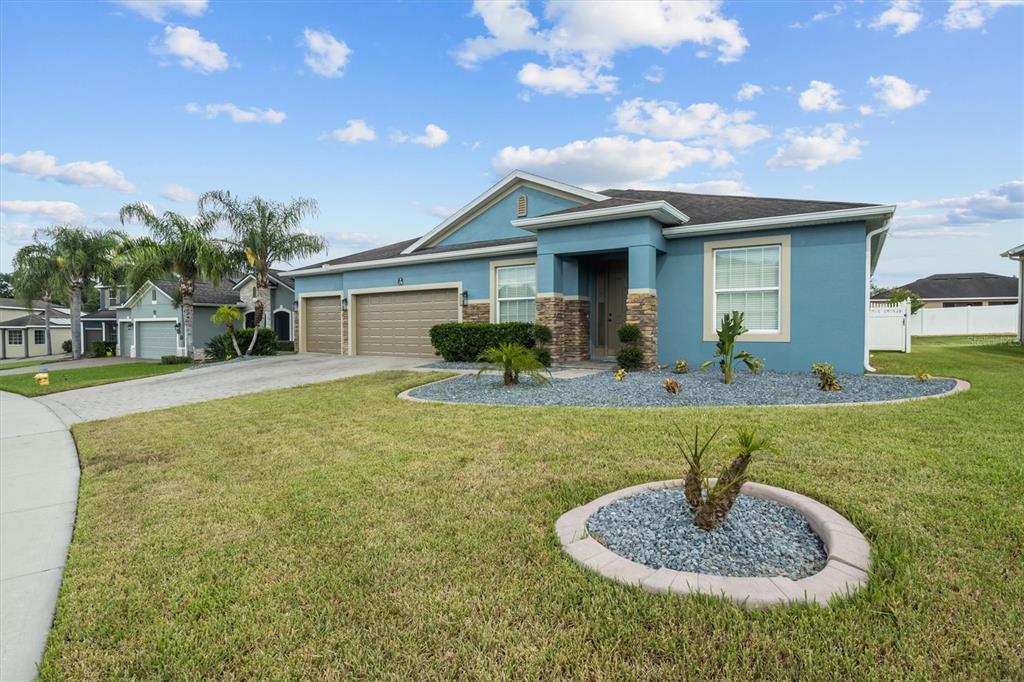 A blue single-story house with a three-car garage and a landscaped front yard — 230 BROAD STREET, WINTER HAVEN, FL