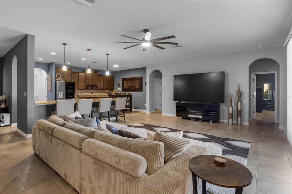 A living room with a large sectional sofa faces a television and an open kitchen — 230 BROAD STREET, WINTER HAVEN, FL