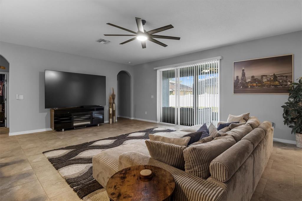 A living room features a large sectional sofa, a television on a stand, and tile flooring — 230 BROAD STREET, WINTER HAVEN, FL
