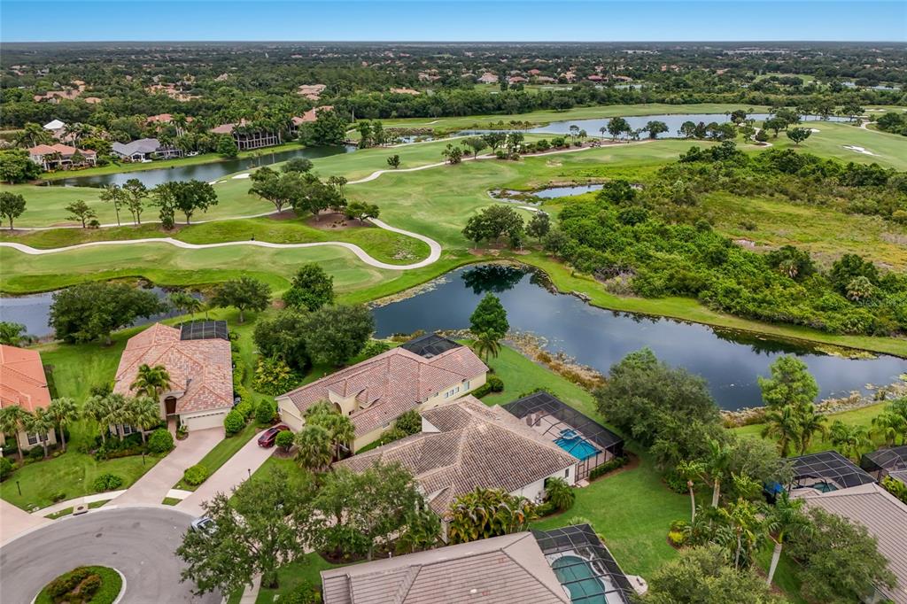 An aerial view shows several suburban homes with pools overlooking a golf course and lake — 12710 STONE RIDGE PLACE, BRADENTON, FL