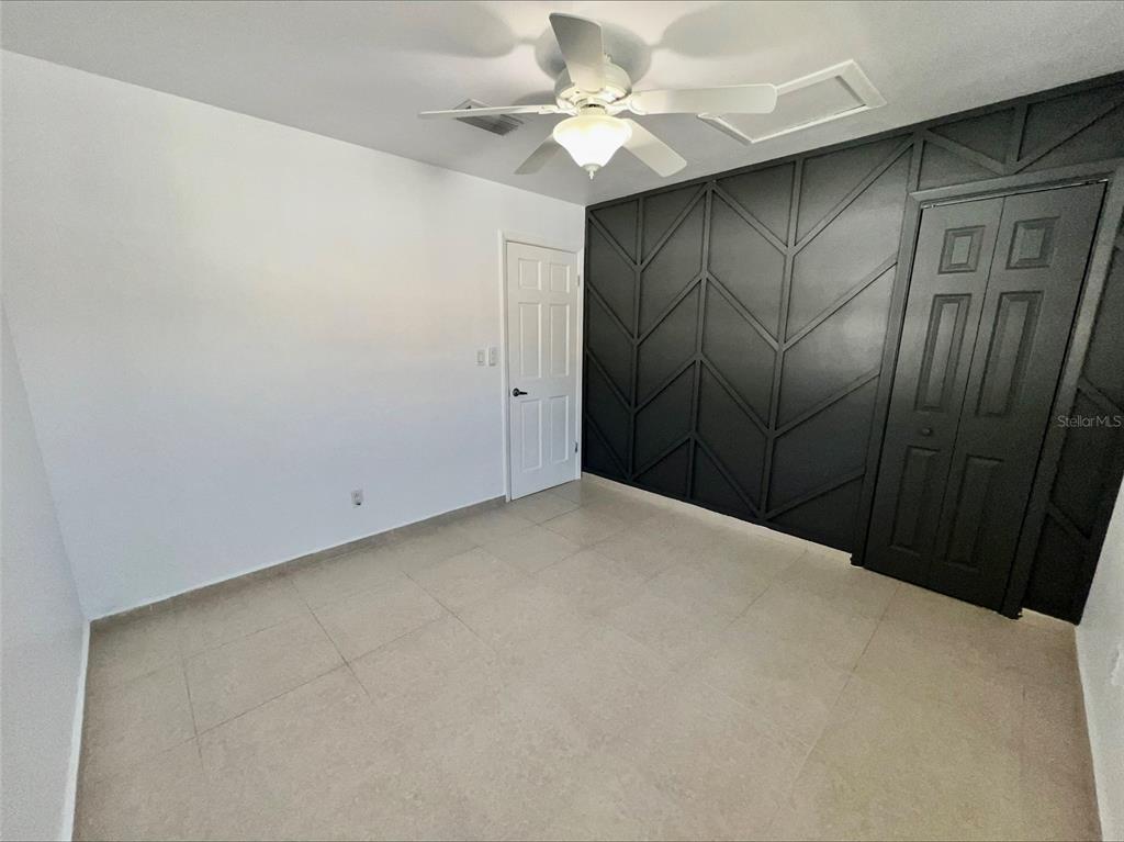 A room with light tile flooring, a white door, and a black geometric accent wall — 1211 LEHIGH STREET, KISSIMMEE, FL