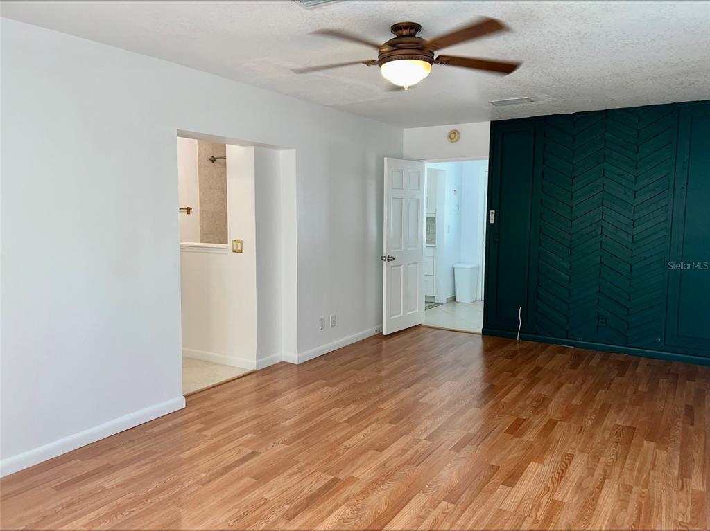 A room with wood-look flooring, a ceiling fan, and a dark green herringbone accent wall — 1211 LEHIGH STREET, KISSIMMEE, FL