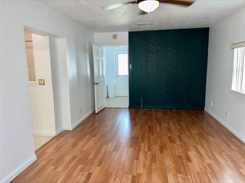 A room with wood-look flooring, a dark green herringbone accent wall, and a ceiling fan — 1211 LEHIGH STREET, KISSIMMEE, FL