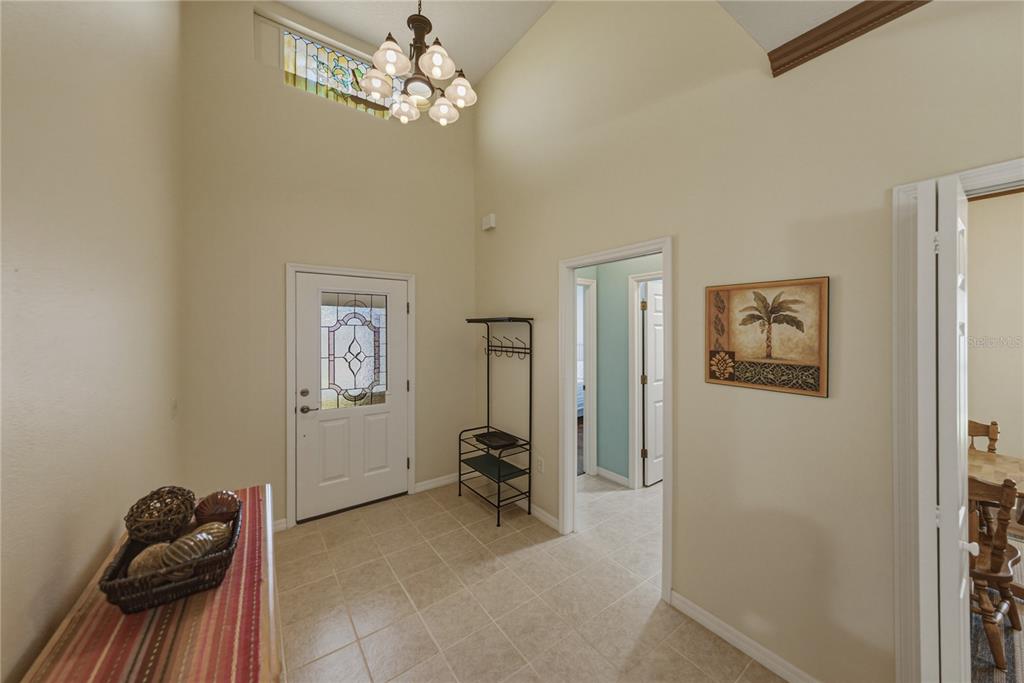 A high-ceilinged entryway features tile flooring, a chandelier, a front door, and interior doorways — 4294 BERWICK DRIVE, LAKE WALES, FL
