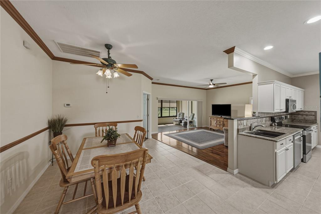 An open-concept kitchen, dining area, and living room with tile and hardwood flooring — 4294 BERWICK DRIVE, LAKE WALES, FL