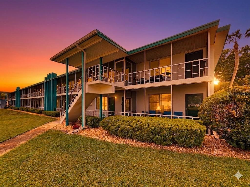 A two-story apartment building with exterior walkways, stairs, and a sunset sky in the background — 1600 W LAKE PARKER DRIVE UNIT C4, LAKELAND, FL