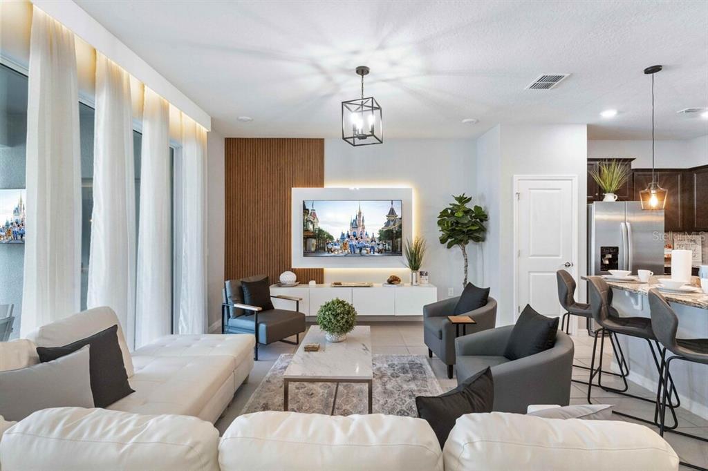A modern living room features a white sectional, grey armchairs, and a wall-mounted television — 107 JETTY WAY, DAVENPORT, FL