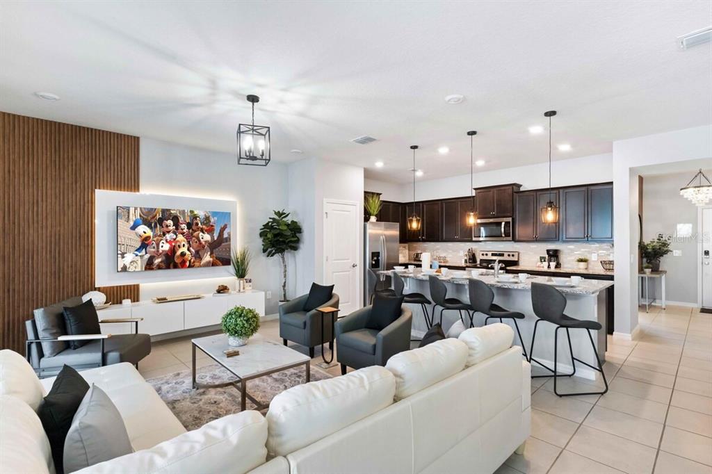 An open-concept living room and kitchen featuring a white sofa, dark cabinetry, and island seating — 107 JETTY WAY, DAVENPORT, FL