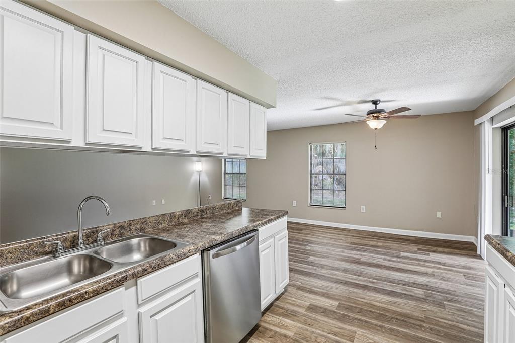 A kitchen with white cabinets and stainless steel appliances overlooks an open living area — 100 E OAK TERRACE DRIVE UNIT D2, LEESBURG, FL