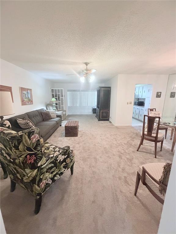A living room features beige carpeting, a dark sofa, a floral armchair, and a dining area — 5301 LAKEFRONT BOULEVARD UNIT C, DELRAY BEACH, FL
