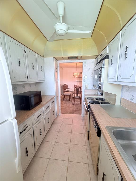 A galley kitchen features white cabinets, laminate countertops, a ceiling fan, and tile flooring — 5301 LAKEFRONT BOULEVARD UNIT C, DELRAY BEACH, FL